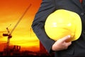 engineer holding yellow helmet for workers security on background of new highrise buildings and Silhouette Crane lifts