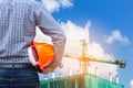 Engineer holding yellow safety helmet in building construction site with crane Royalty Free Stock Photo