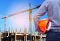 Engineer holding yellow safety helmet in building construction site with crane Royalty Free Stock Photo