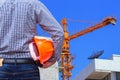 Engineer holding yellow safety helmet in building construction site with yellow crane Royalty Free Stock Photo