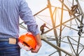 Engineer holding yellow safety helmet with electricians working on pylon construction tower Royalty Free Stock Photo