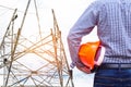 Engineer holding yellow safety helmet with electricians working on pylon construction tower