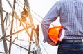 Engineer holding yellow safety helmet with electricians working on pylon construction tower