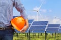 Engineer holding yellow safety helmet front solar photovoltaic and wind turbines power station