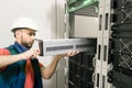 An engineer installs a new battery pack into an uninterruptible power supply. Replacing the power module in the server room rack.