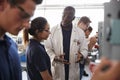 Engineer instructing female apprentice at a drill press