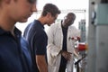 Engineer instructing male apprentice at a drill press