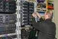 Engineer with laptop sitting in server room. The technician connects the optical wires in the data center. The system