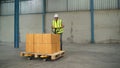 The engineer lifts the boxes to a cart and drags them in a warehouse.