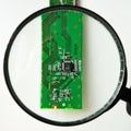 Engineer looking at a circuit board through a magnifying glass