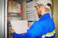 Engineer looks at the electrical drawing on the background of the automation panel