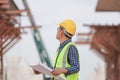 Engineer man with blueprint checking project at construction site, Foreman worker holding plan in building site Royalty Free Stock Photo