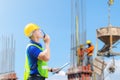 Engineer man in hardhat and safety vest talks on two-way radio, Worker man holding clipboard checklist at construction site