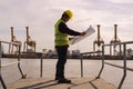 Engineer man wearing safety helmet and hold blueprints at a cargo port facility Royalty Free Stock Photo