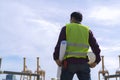 Engineer man wearing safety helmet and hold blueprints at a cargo port facility Royalty Free Stock Photo