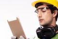 Engineer man working on digital tablet computer at worksite or industry. Handsome young industrial worker were hard hat, safety