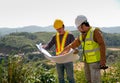 Engineer manager man discuss with his team who hold construction plan and stay in front of mountain view and  high voltage pole Royalty Free Stock Photo