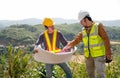 Engineer manager man discuss with his team who hold construction plan and stay in front of mountain view and  high voltage pole Royalty Free Stock Photo