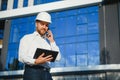 Engineer next to building cranes. Concept - large construction project. Architect directs the construction process. Drawings and Royalty Free Stock Photo