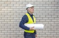 An attentive architect in a white helmet examines a project. On a bright sunny day. Architect with diagrams in hands on a white