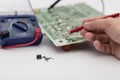 Engineer repairing electronic circuit board with multimeter. Royalty Free Stock Photo