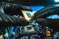 Engineer repairman holding hands CPU to insert into the socket of the motherboard. Technology hardware in the neon light