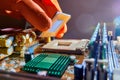 Engineer repairman holding hands in orange gloves, processor to insert in socket pc motherboard. Neon light. Close up