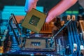 Engineer`s gloved hand is holding the CPU chip on the background of the motherboard. High-tech hardware microelectronics Royalty Free Stock Photo