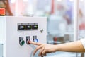 Engineer`s hand push red button to shutdown temperature control machine. Temperature control panel cabinet contain digital screen Royalty Free Stock Photo