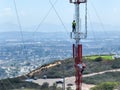Engineer with safety equipment on high tower for working telecom communication maintenance.