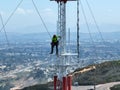 Engineer with safety equipment on high tower for working telecom communication maintenance.