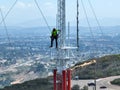 Engineer with safety equipment on high tower for working telecom communication maintenance.