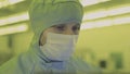 Engineer scientist in sterile suits, mask. are in a clean zone looking at a process technologically advanced factory