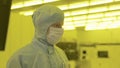 Engineer scientist in sterile suits, mask. are in a clean zone looking at a process technologically advanced factory