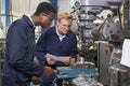 Engineer Showing Apprentice How to Use Drill In Factory