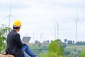 An engineer sits at his laptop looking at clean energy wind turbine project to generate electricity