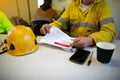 Engineer sitting placing safety hard hat on the table coffee cup pen reviewing JSA risk assessment Royalty Free Stock Photo