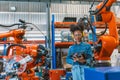 Engineer smart woman worker working programing robotic welding machine. Black teen girl work in advance modern factory Royalty Free Stock Photo