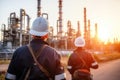 Engineer survey of oil refiner and control worker from portable radio on storage tank in sunset background