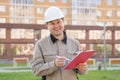 Engineer with a tablet in his hands, smiling, looking at the new building