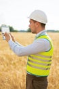 an engineer with a tablet in his hands stands in the middle of a green field, an agronomist in a field with wheat checks the