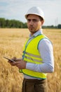 an engineer with a tablet in his hands stands in the middle of a green field, an agronomist in a field with wheat checks the