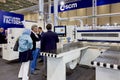 An engineer talks about the operation of woodworking equipment to a group of visitors at an exhibition