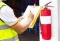 Engineer technician checking fire extinguisher writing on clipboard at warehouse