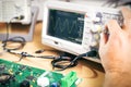 Engineer tests electronic components with oscilloscope in the service center