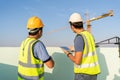 Engineer use a tablet introducing the foreman to inspect and supervise the position of the construction crane at construction site