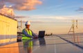 Engineer using laptop at solar panels on rooftop at sunset sky, An engineer working at a photovoltaic farm. Eco technology for