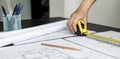 An engineer is using a tape measure to measure the plans of the house that he designs. Royalty Free Stock Photo