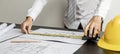 An engineer is using a tape measure to measure the plans of the house that he designs. Royalty Free Stock Photo