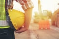 Engineer wear a hard hellmet and holding blueprint on Engineer holding helmet at road construction site with machinery background, Royalty Free Stock Photo